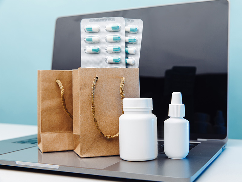 Medikamentenlieferung in Ratzeburg: Papier¬tüten mit Tabletten und Arzneiflaschen neben Laptop zur Online Bestellung.